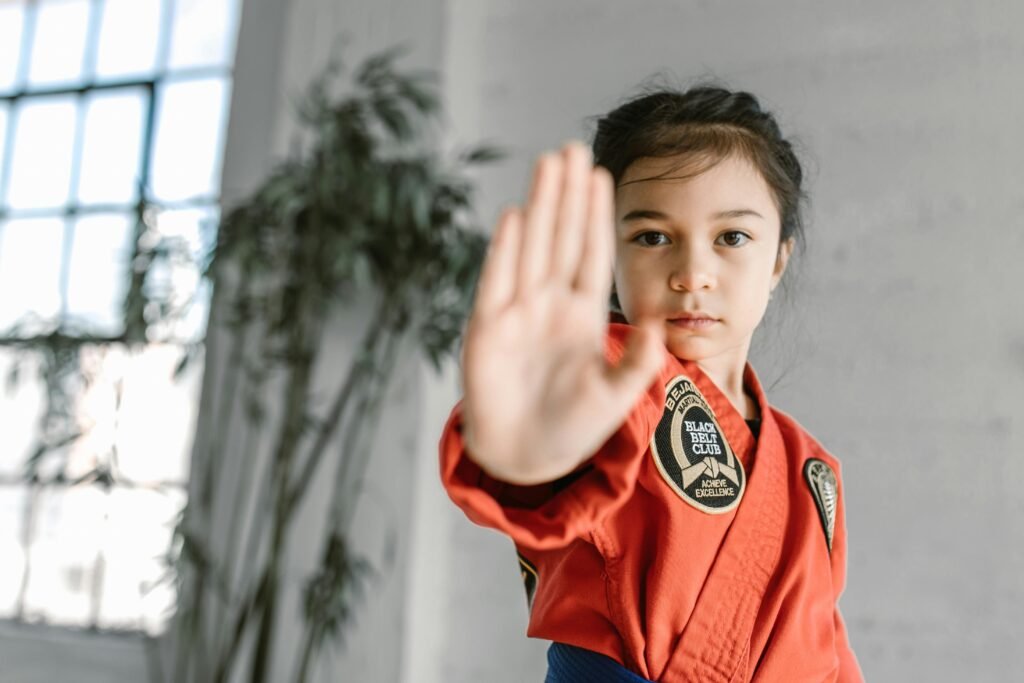 A determined young girl in martial arts attire practicing inside a dojo.